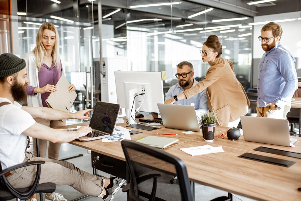 Business-Team im Konferenzraum mit Laptops und Präsentationstafeln.